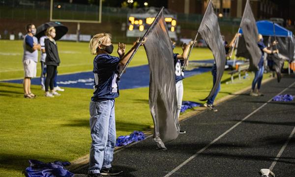 Color Guard members spin flags on sidelines